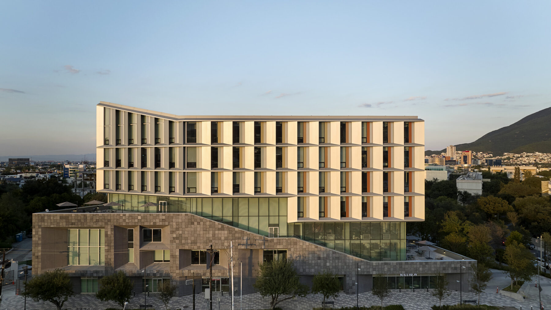 Aerial elevational photo of building exerior with warm sunlight across the facade with exterior stair and terraces wrapping around the building
