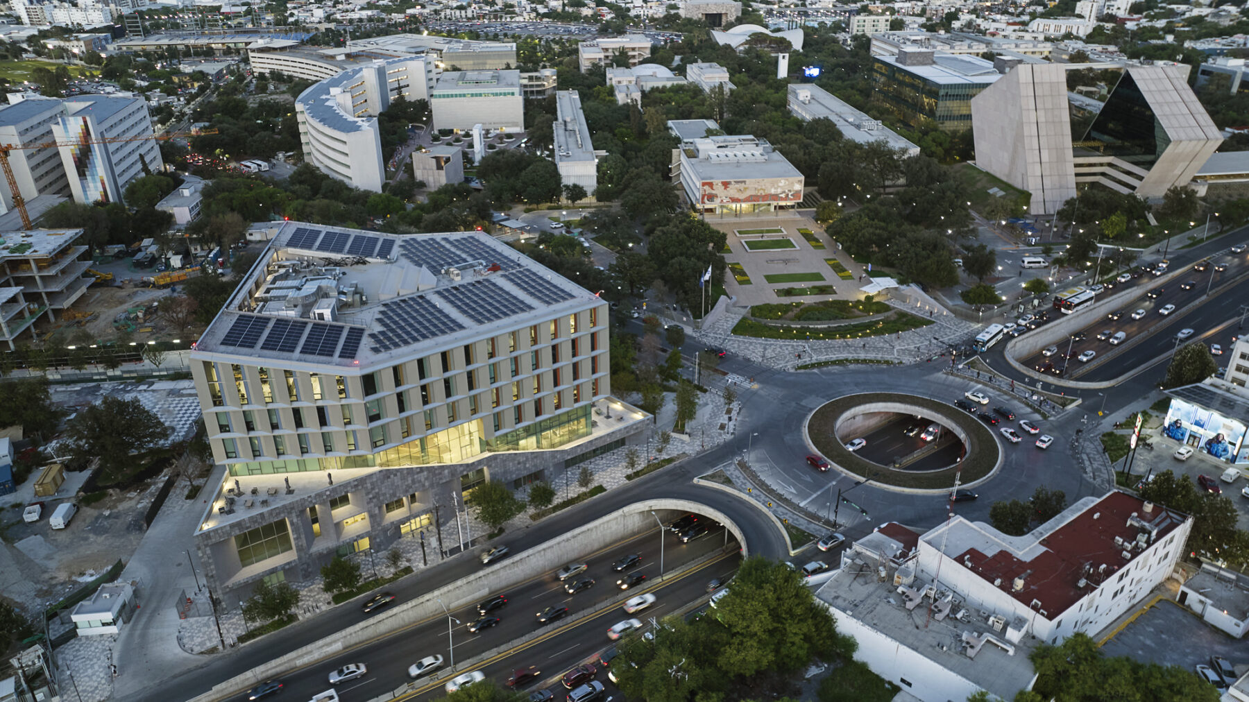 Aerial photo taken at dusk with building interior glowing and views to campus beyond