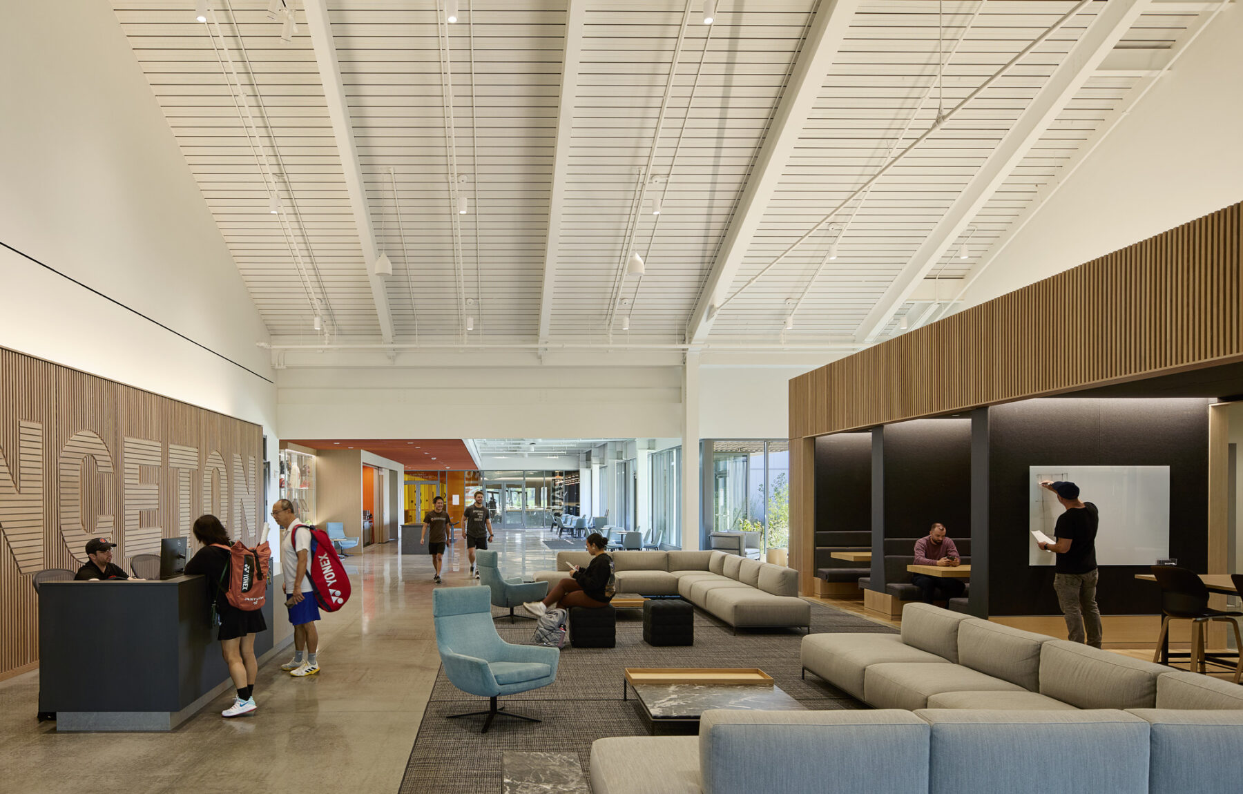 Photo of lobby lounge space with couches, flexible furniture, and open space to see the indoor competition spaces in the distance