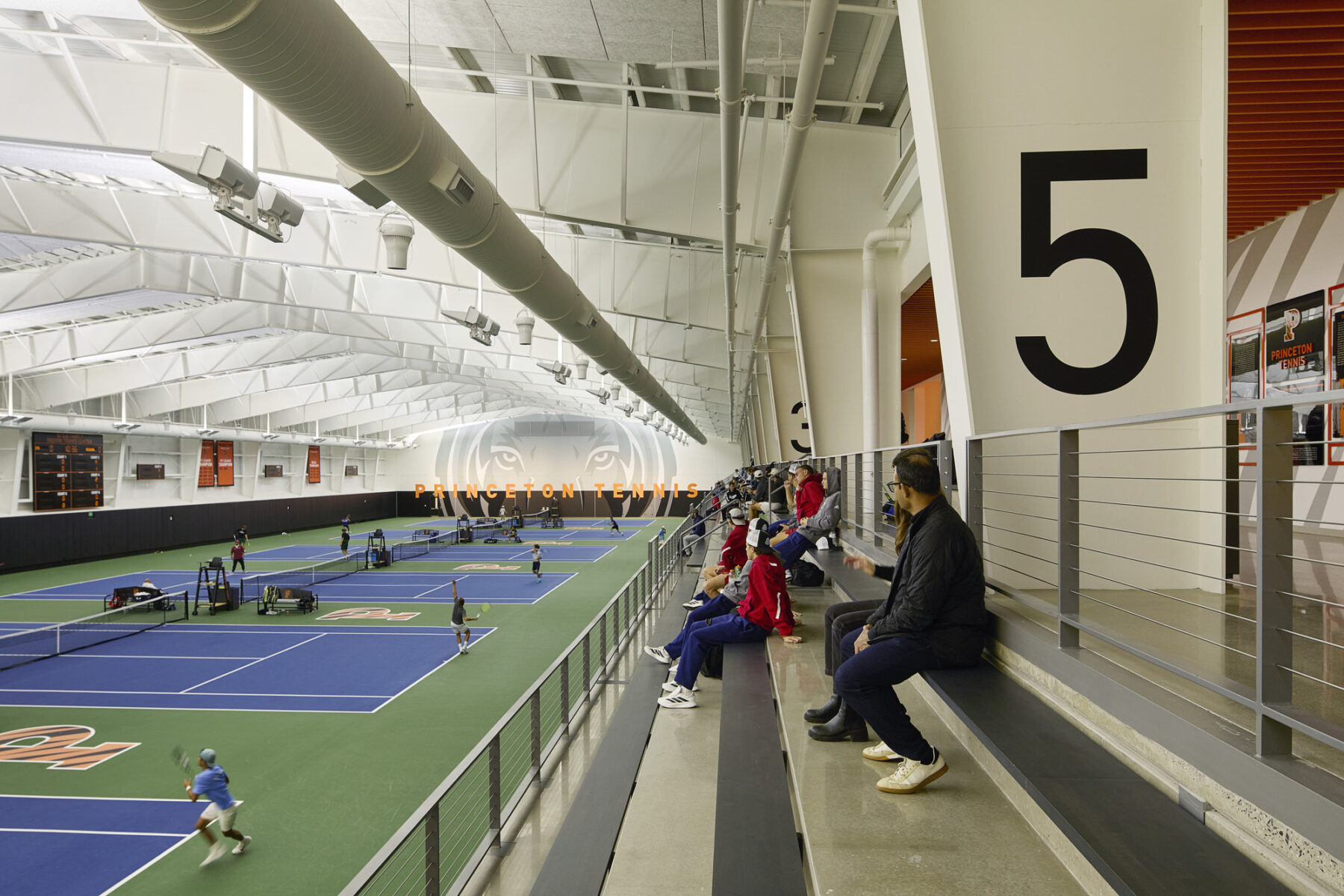 Photo of indoor tennis area viewing down from the upper level bleachers