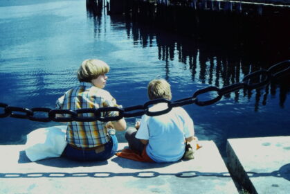 photo of two children sitting at the waterfront edge enjoying the view of the harbor