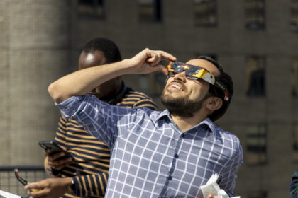 Sasaki staff member with solar glasses observes the 2024 solar eclipse from the office roof deck