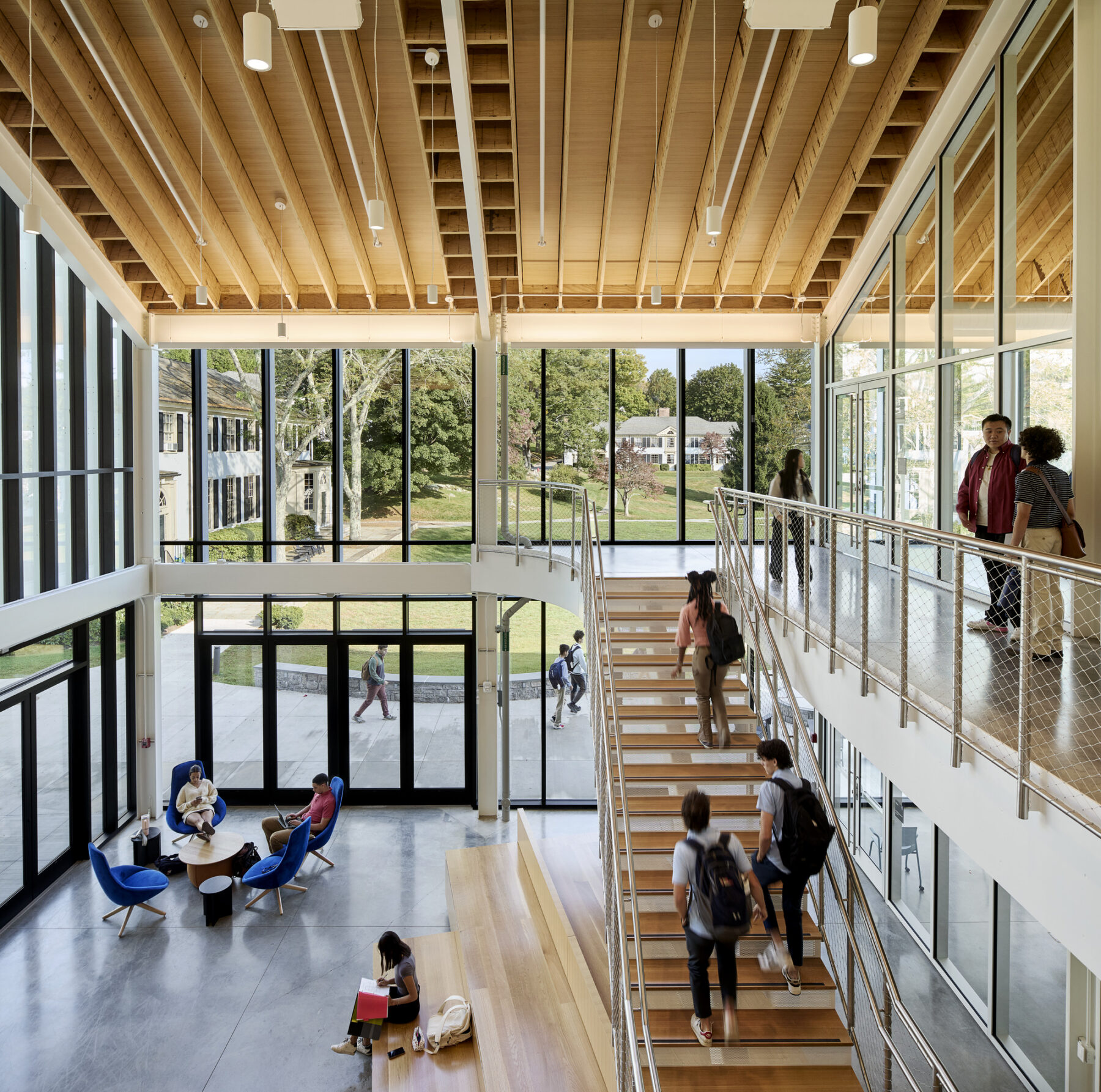 Photo of Living Room interior viewed from the second level balcony facing the double height glazing with views out to campus