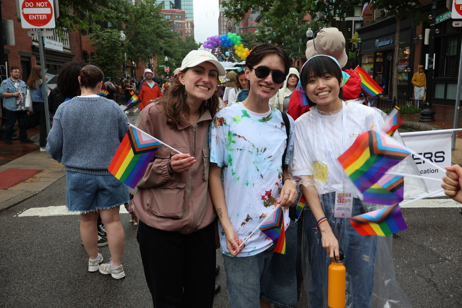 Three people pose for a photo holding rainbow flags