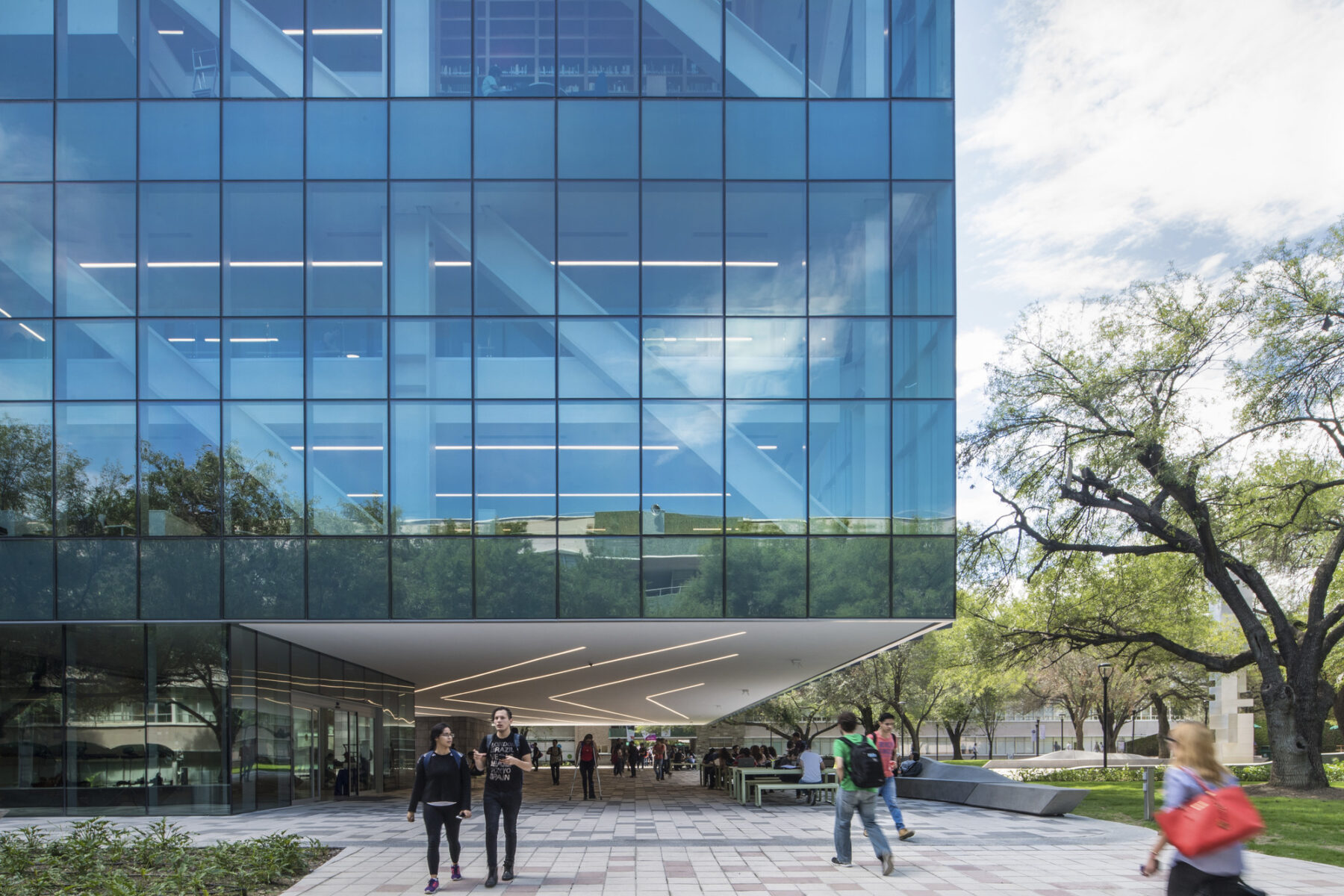 photo of large glass building with people walking underneath
