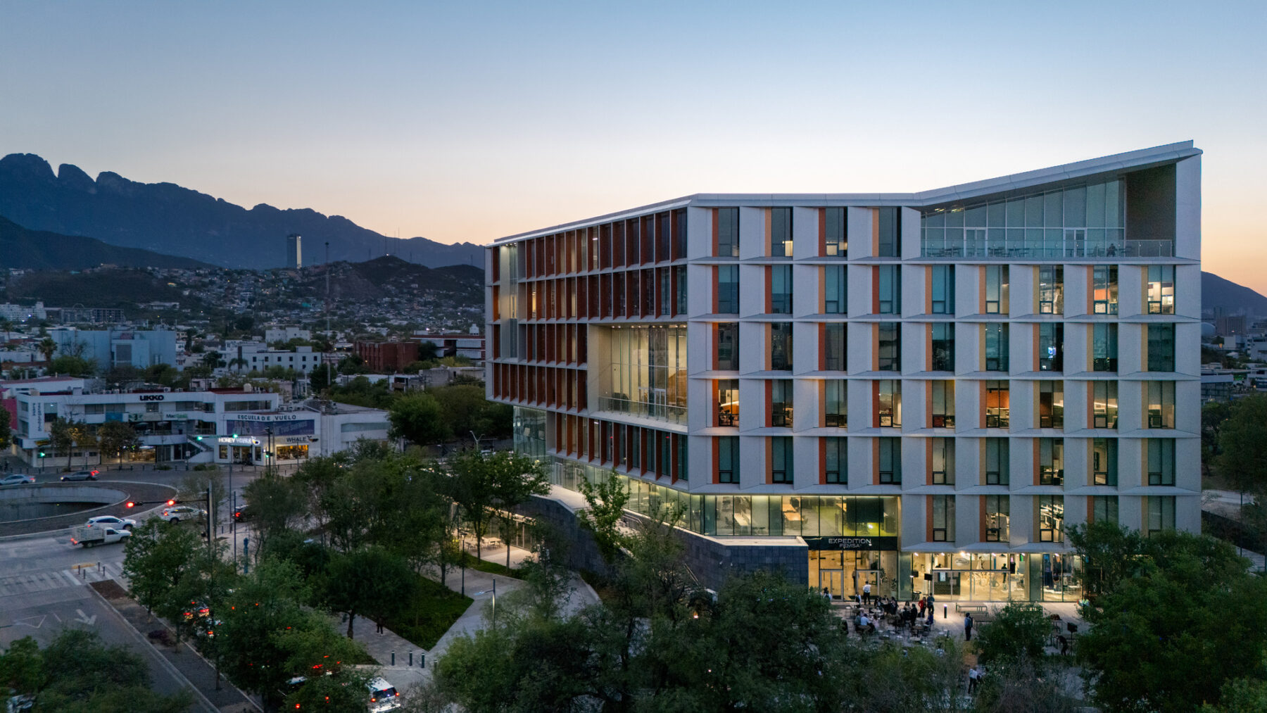 aerial view of multi-story building at dusk, with view to city and mountains