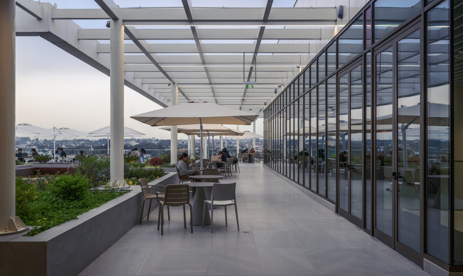 View of level 7 terrace with the city in the background and pergola, seating and building in the foreground