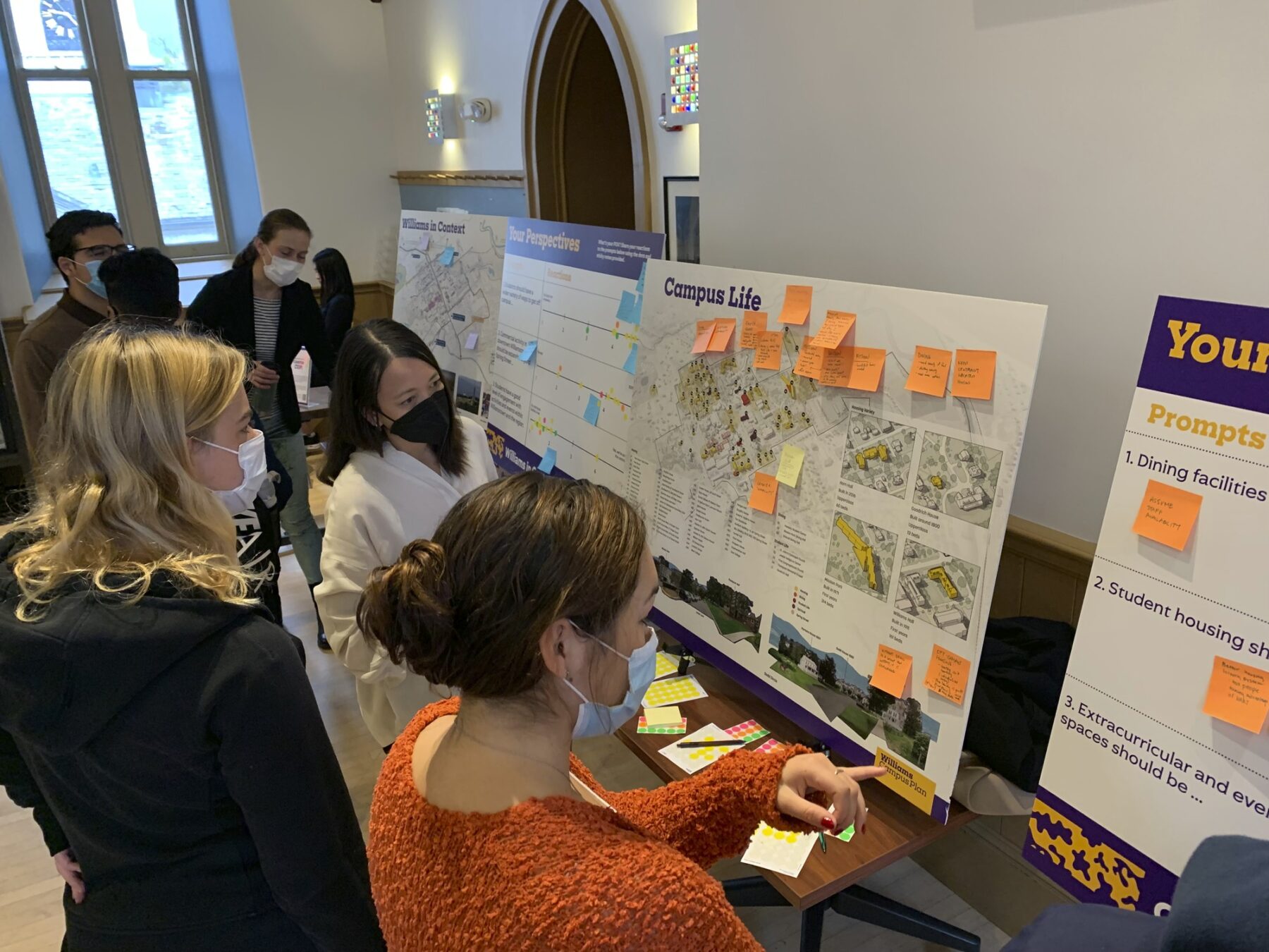 Photo of students interacting with poster boards and sticky notes, providing feedback on campus plan