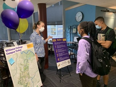 Photo from campus engagement event with balloons in school colors and people looking at poster displays
