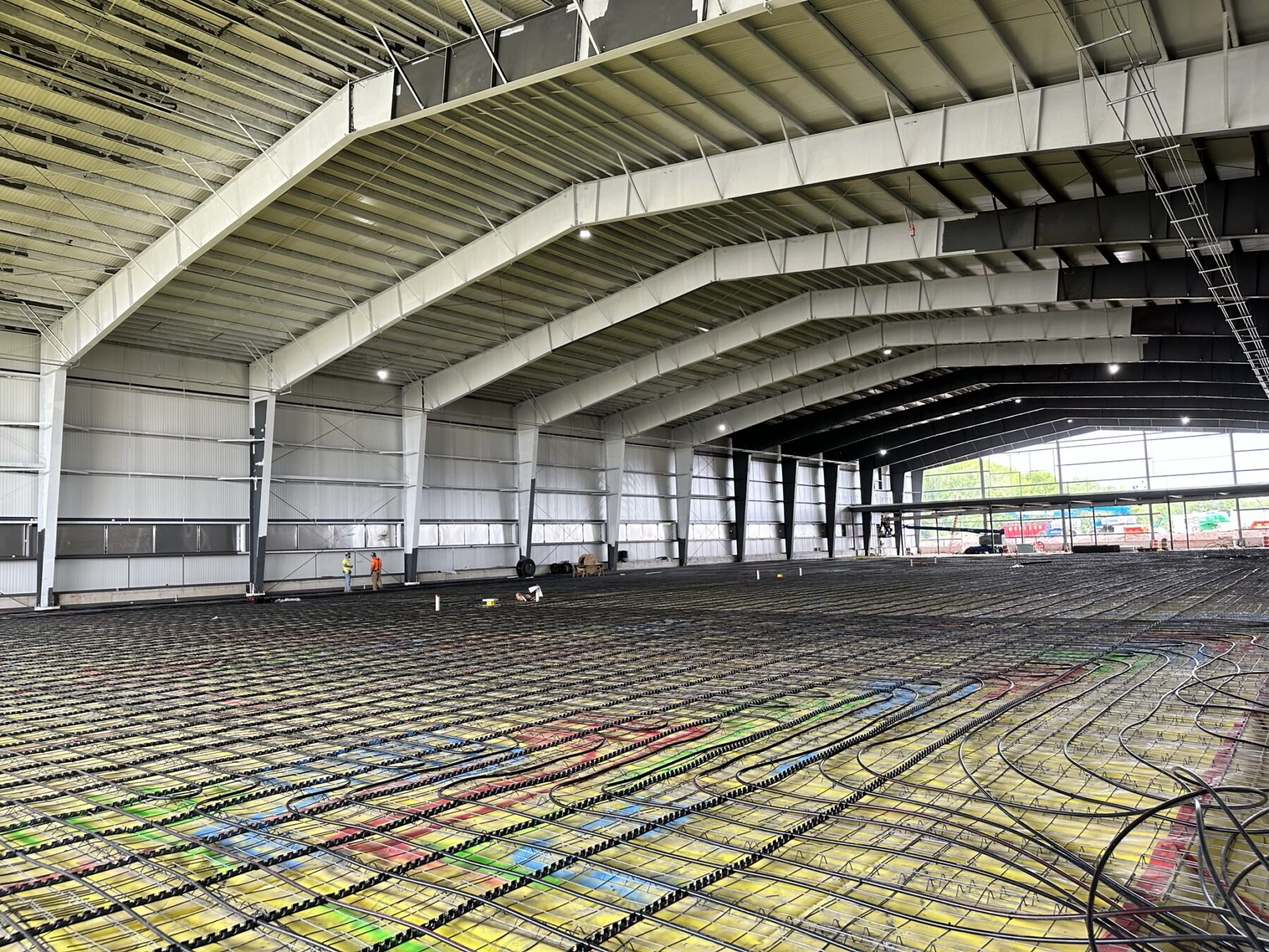construction photo showing a slab with pipes running along the surface in a large space