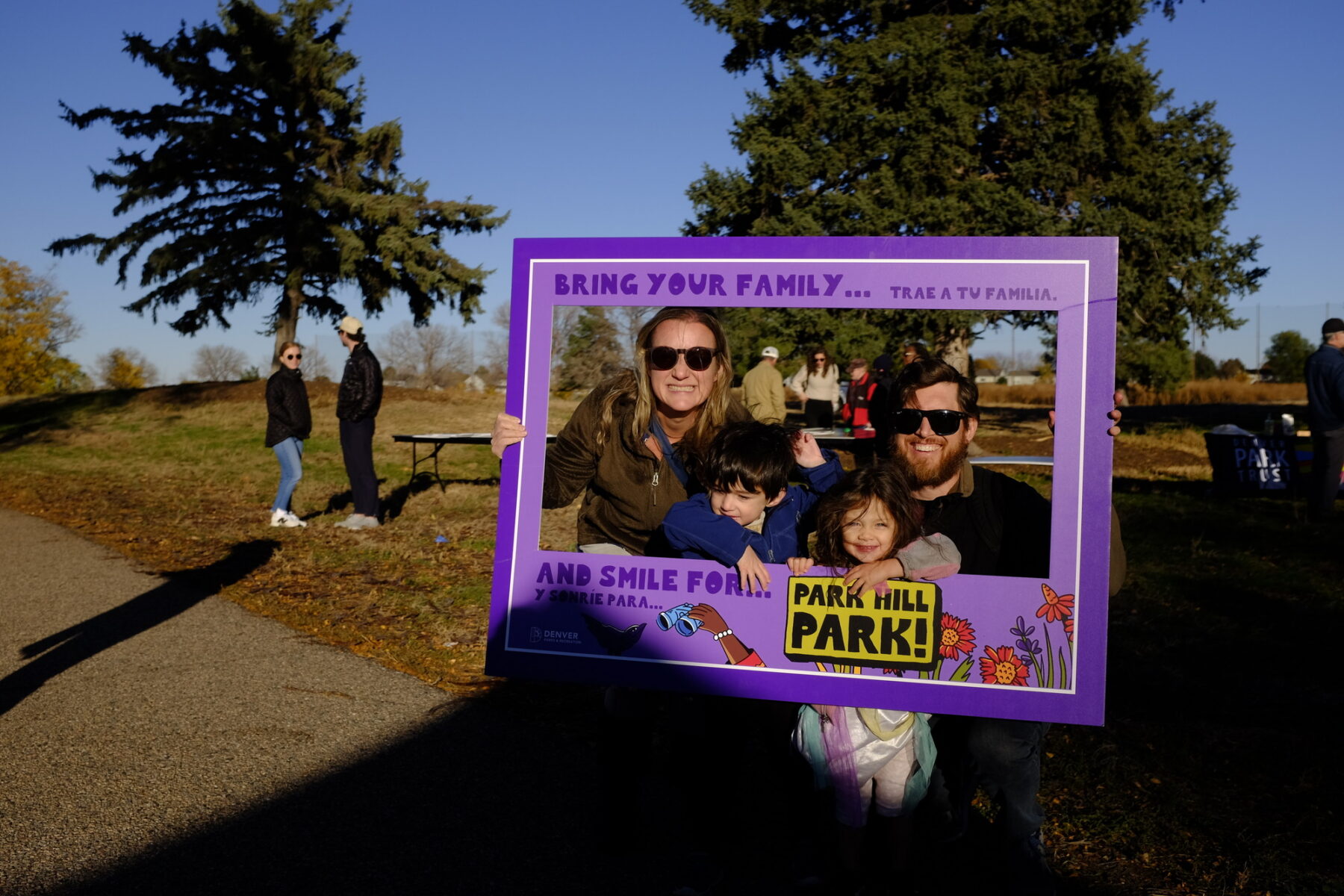 Photo of community engagement activity at the Park Hill Park site with a family holding a colorful cardboard photo frame