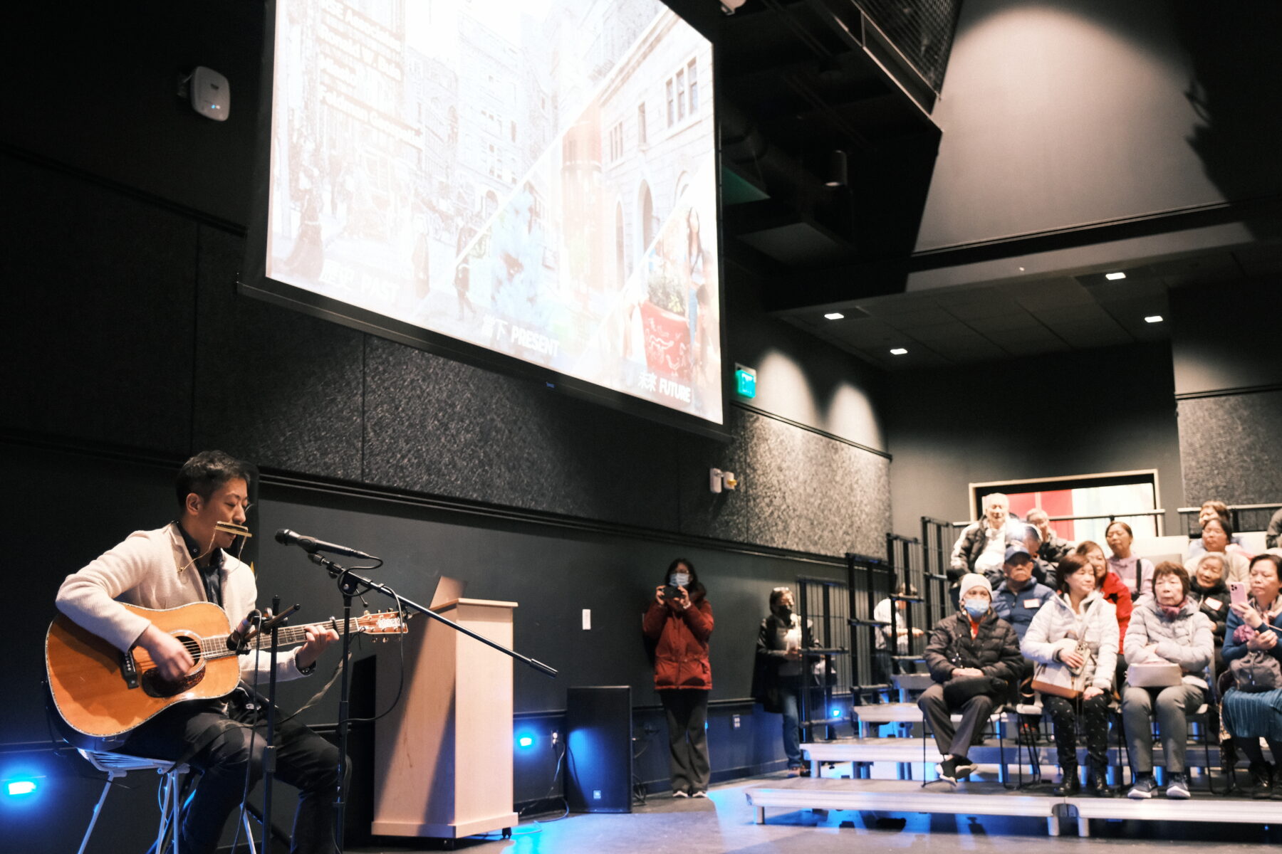 Photo of a person playing a guitar for an audience