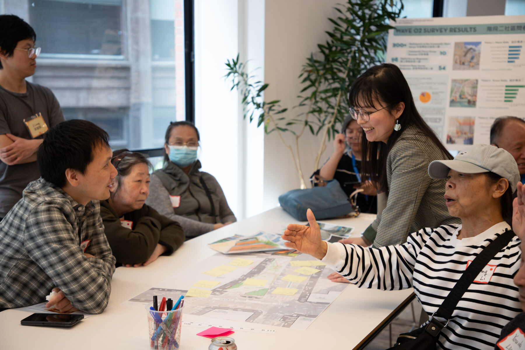 Photo of people sitting around a table, talking and gesturing to designs on paper
