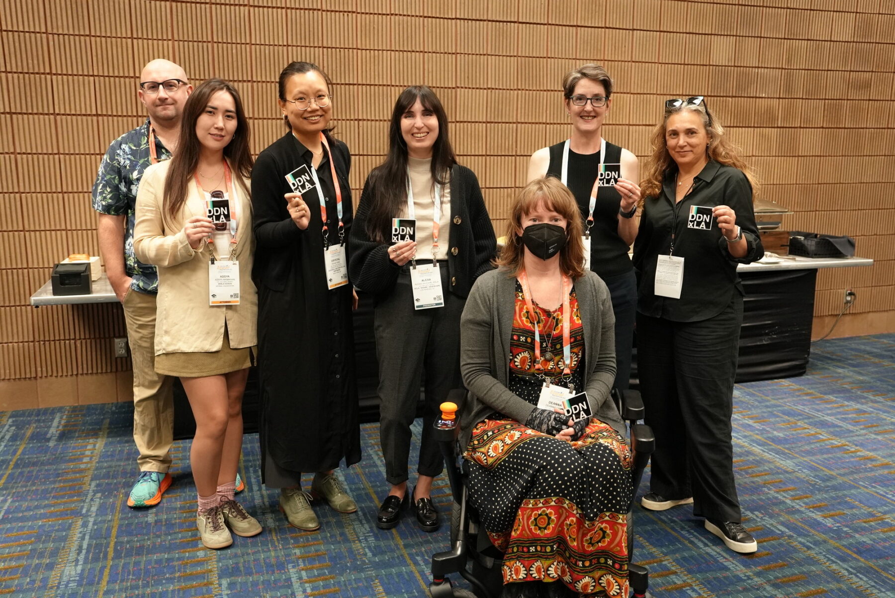 Seven people smiling and holding DDNxLA cards