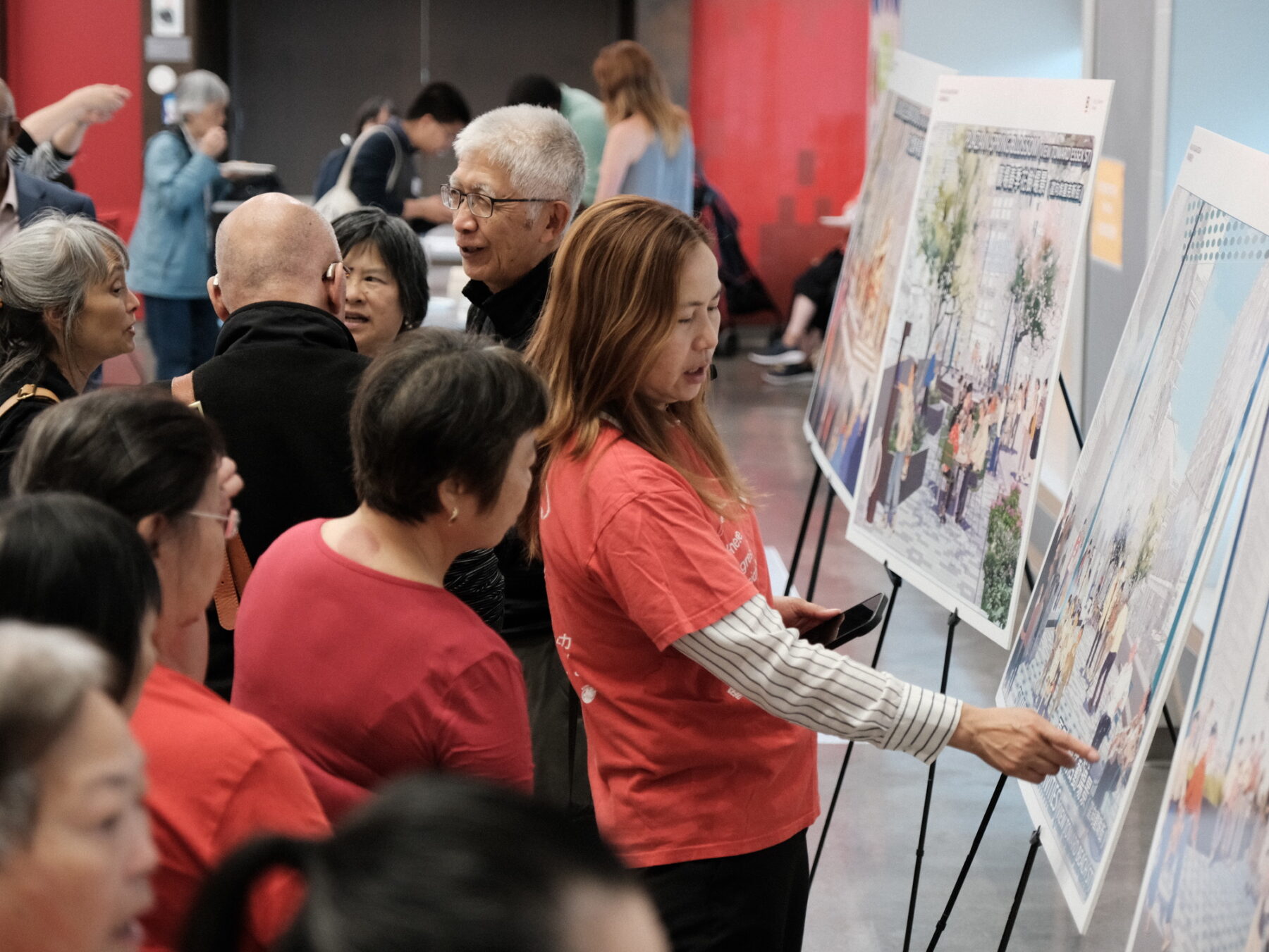 Photo of people standing in front of a paper board talking and gesturing to designs on it