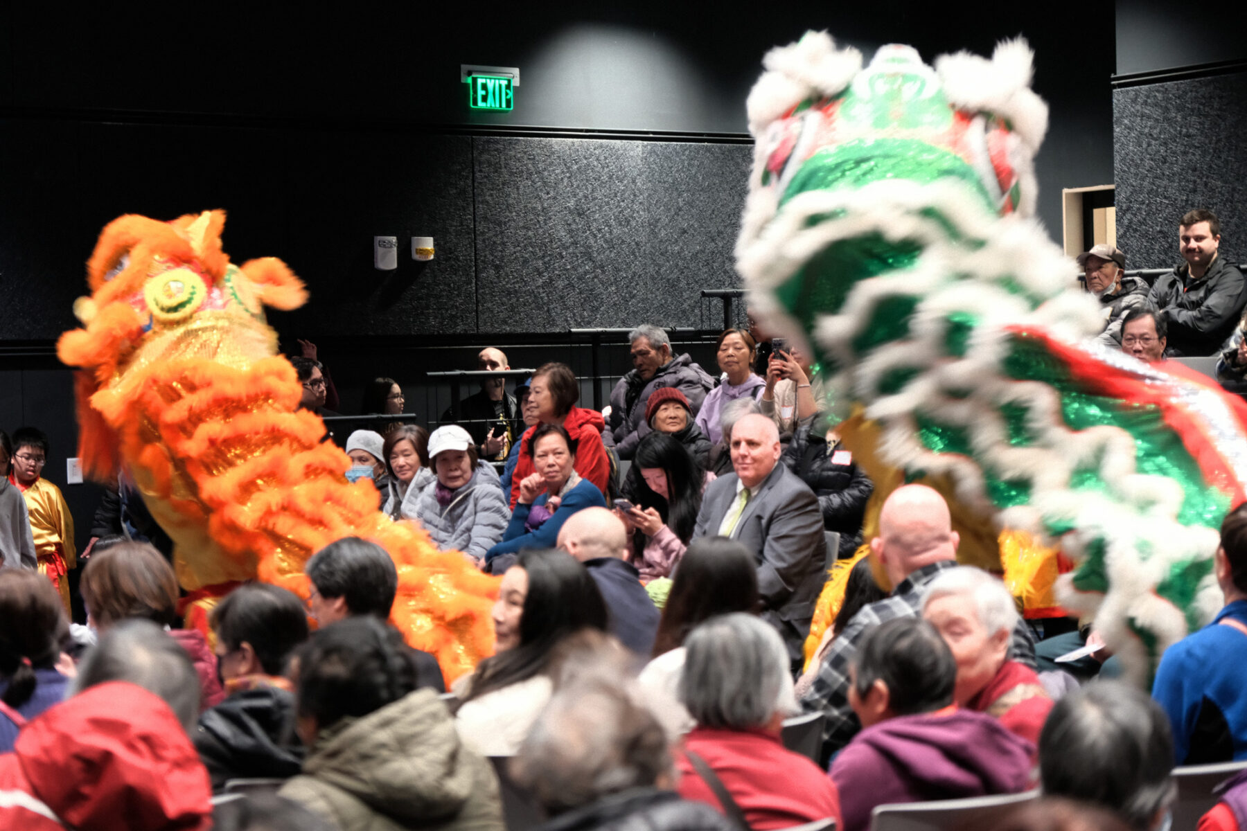 People sitting in an auditorium setting enjoying a dragon dance performance