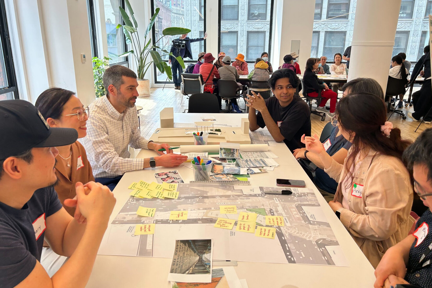 People sitting at a table discussing designs on trace paper and post-its